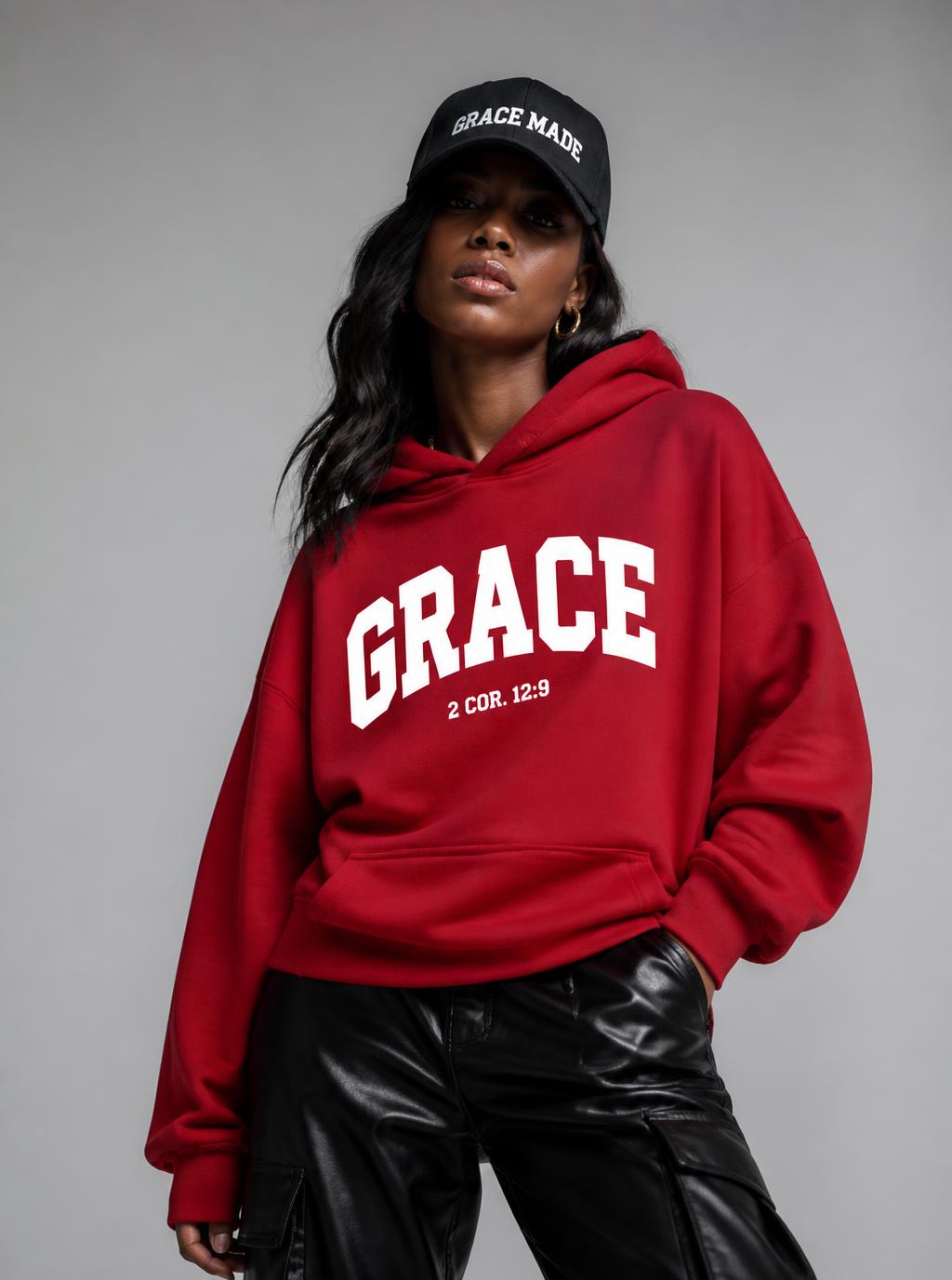 Black woman in red Grace Scripture hoodie, faux leather pants, and black Grace Made cap